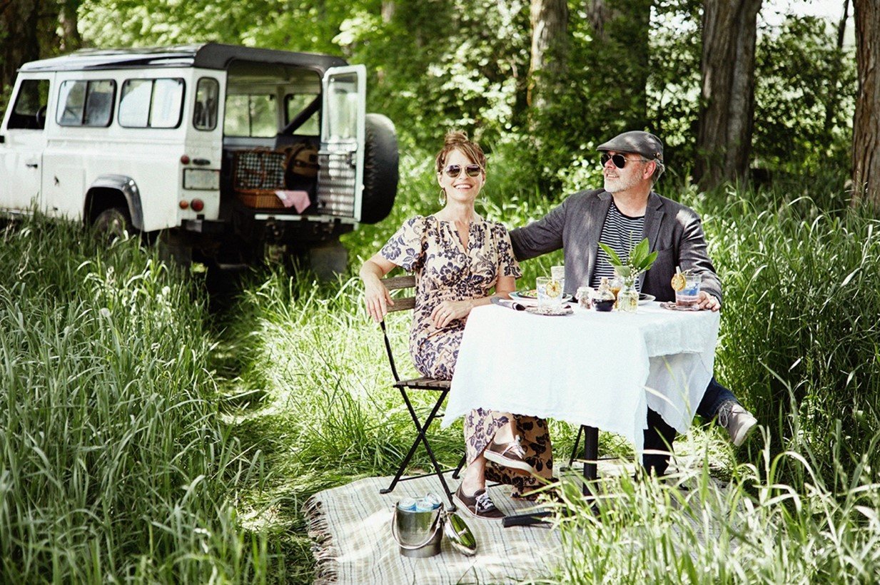 Malcom and Shelly are in a field, sitting at a small table.